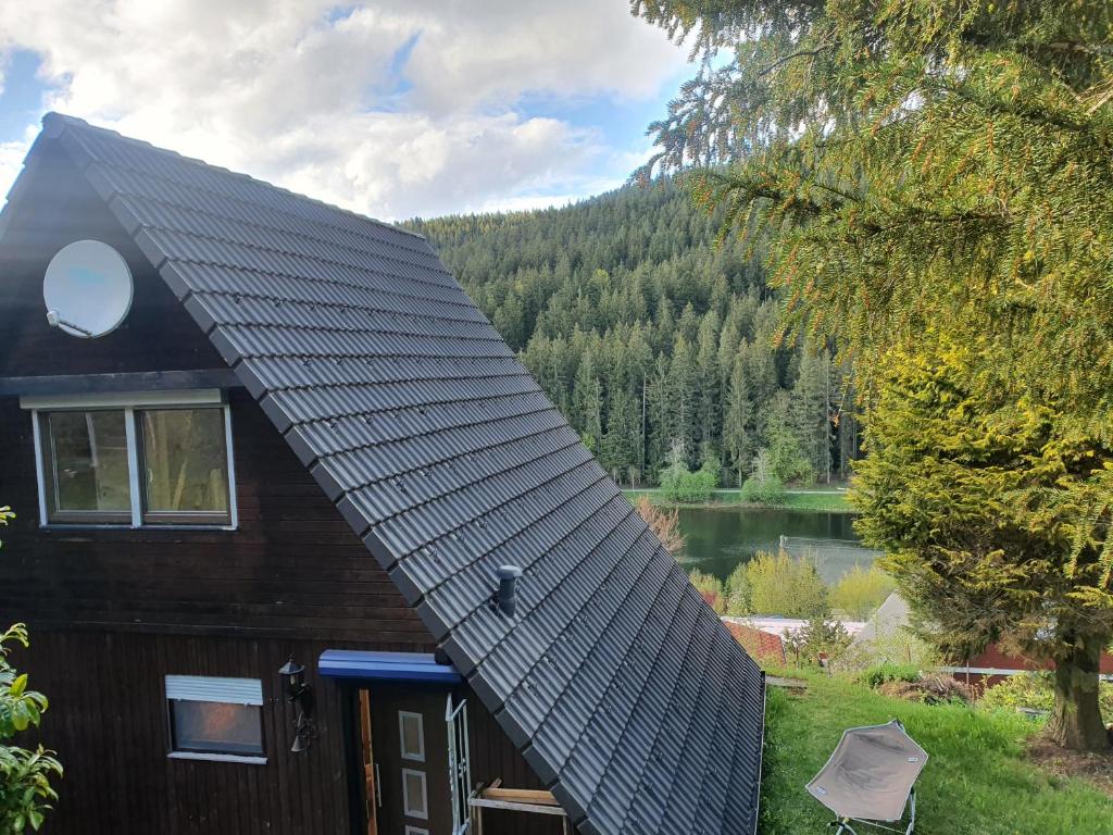 a house with a gambrel roof with a lake at Haus Adler - Komplettes Ferienhaus am Badesee in Erzgrube