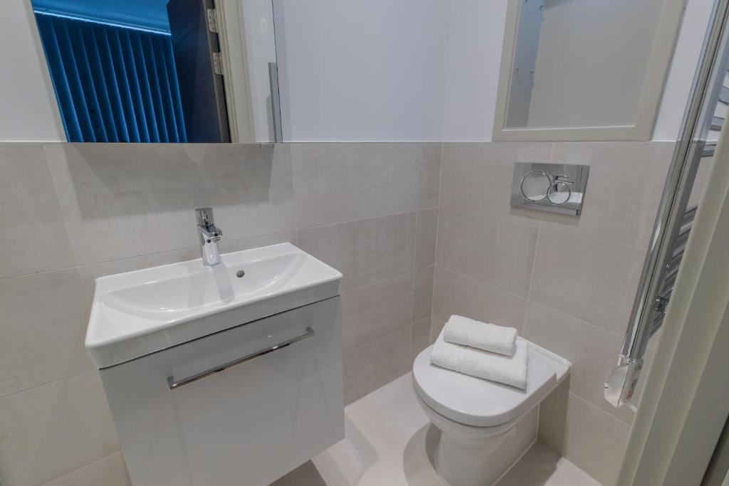 a white bathroom with a sink and a toilet at Paddington Gardens in London