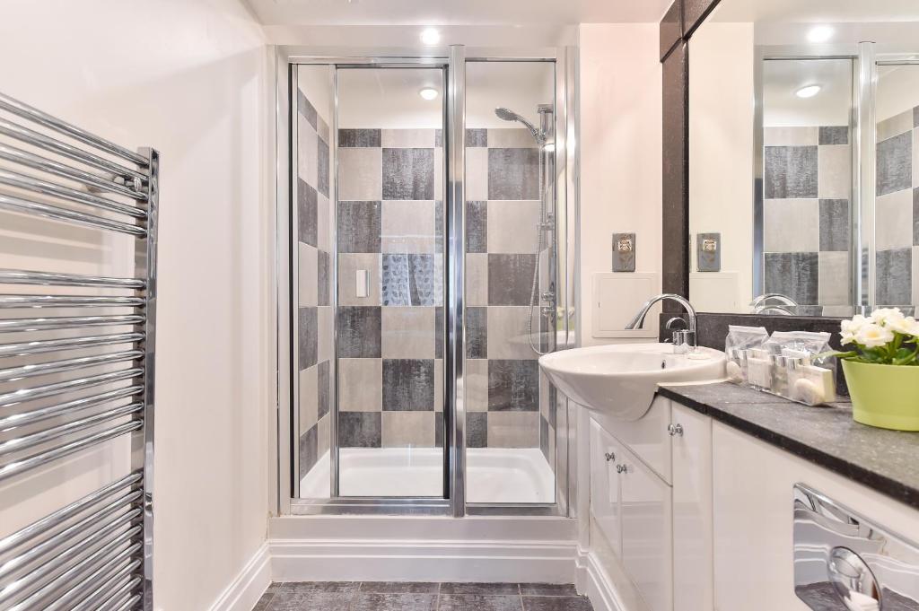 a white bathroom with a shower and a sink at Paddington Gardens in London