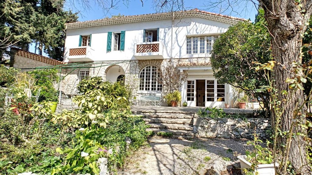 uma casa branca com uma árvore em frente em Propriété LES TYNTARIDES proche port piscine privée em Cassis