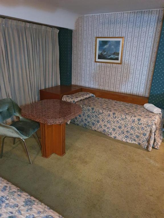 een hotelkamer met een bed, een tafel en een stoel bij Apartamentos Plaza in Rosario