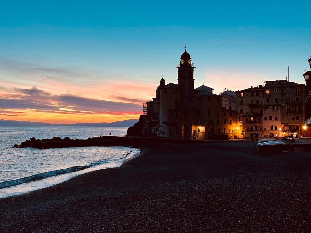 a building with a clock tower on a beach at sunset at La Lampara Camogli in Camogli