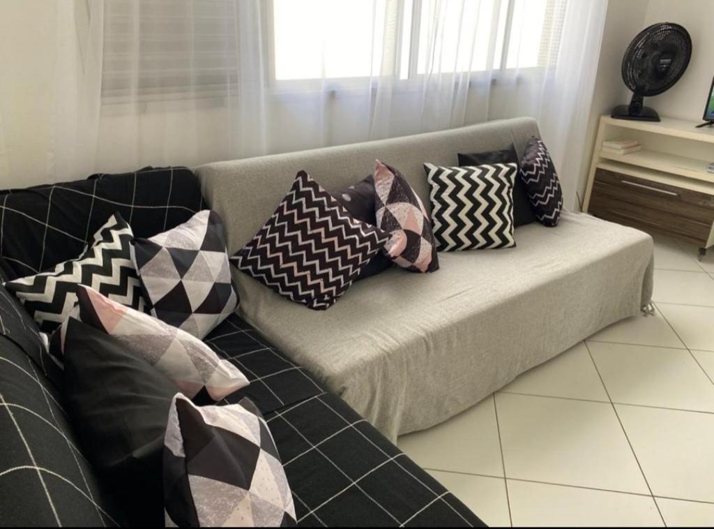 a couch with pillows on it in a living room at Apartamento Praia in Guarujá