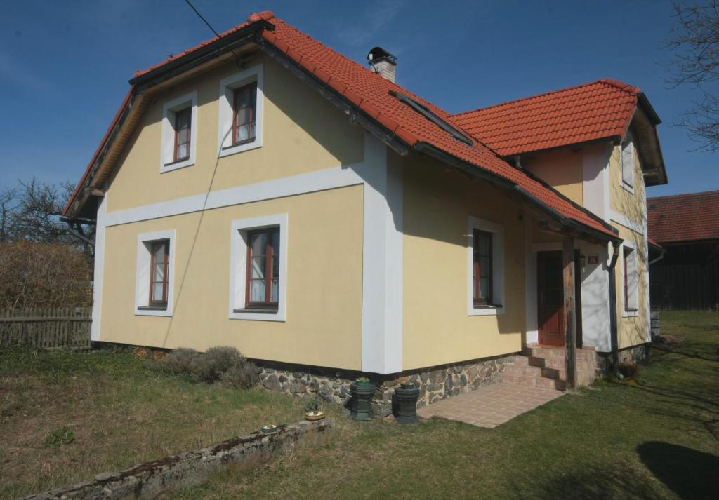 una pequeña casa blanca y amarilla con techo rojo en Apartmán V sadu en Míšov