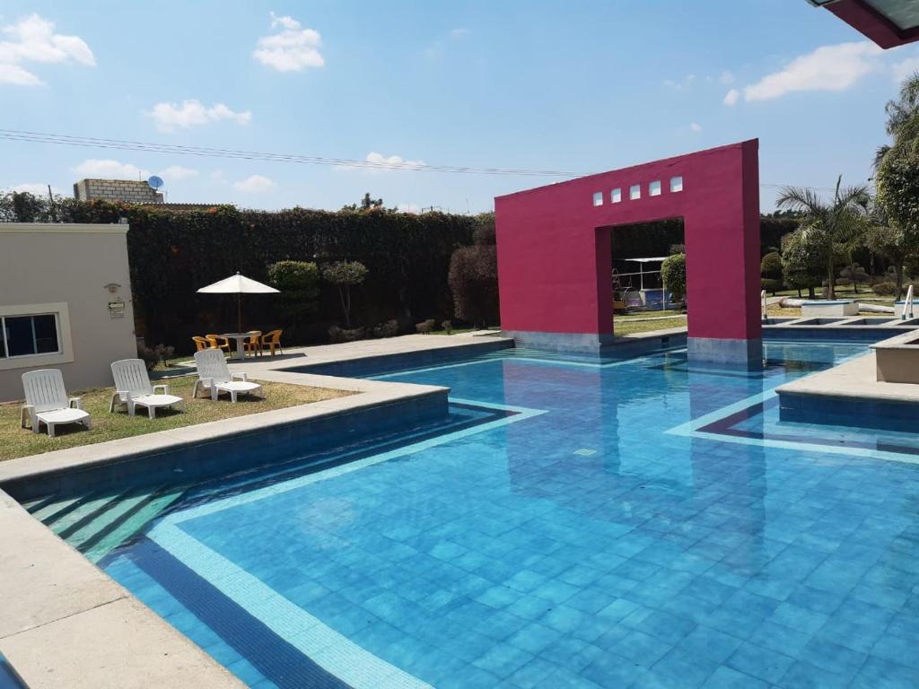 a swimming pool with a red building in the background at Hotel Quinta Loriffe in Cuautla Morelos