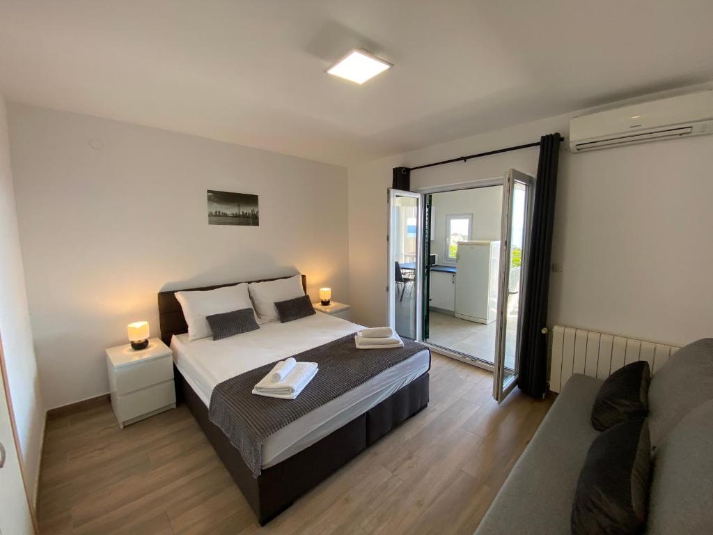 um quarto com uma cama e uma porta de vidro deslizante em Maritom Apartments em Baška Voda