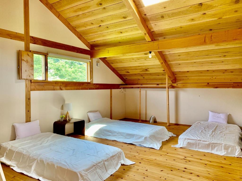two beds in a room with wooden ceilings at Kitaarupusu ichibō no ie - Vacation STAY 96488v in Omachi