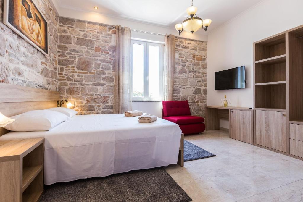 a bedroom with a bed and a red chair at B&B Giardin exclusive rooms and suite in Zadar