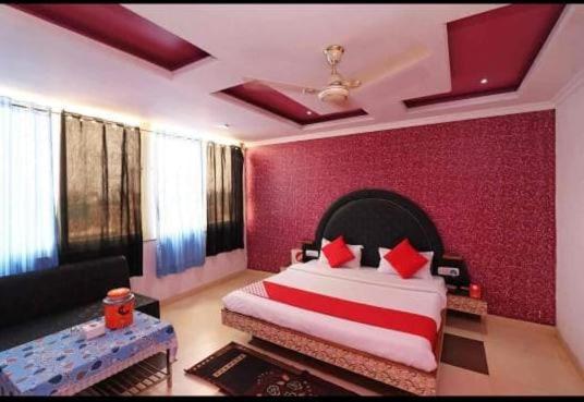 um quarto com uma cama grande e uma parede vermelha em Hotel Rock View em Pachmarhi
