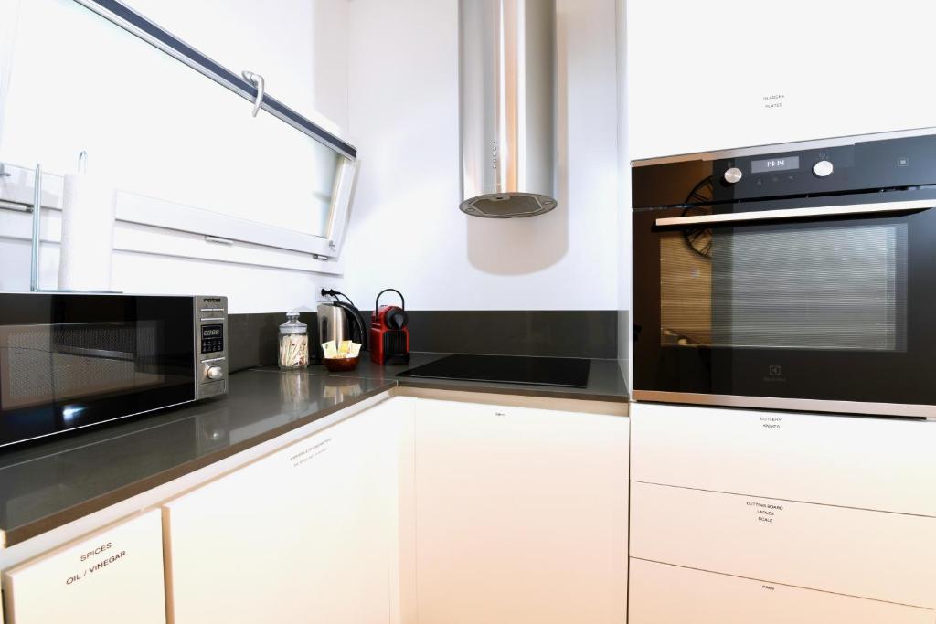 a kitchen with white cabinets and a black microwave at Lake Modern Suites - Free Parking in Lugano