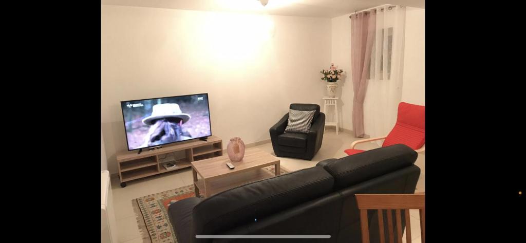ein Wohnzimmer mit einem Sofa und einem Flachbild-TV in der Unterkunft Appartement dans uns corps de ferme in Follainville-Dennemont