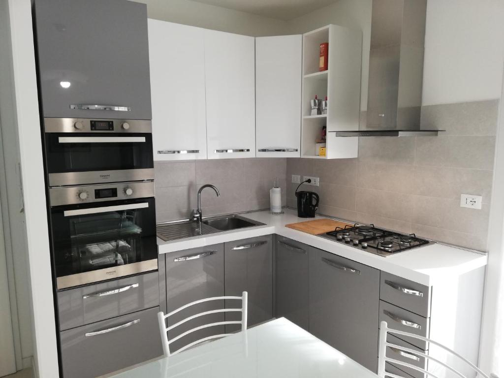 una cocina con armarios blancos y electrodomésticos de acero inoxidable en Nuovissimo appartamento con terrazza en Alguer