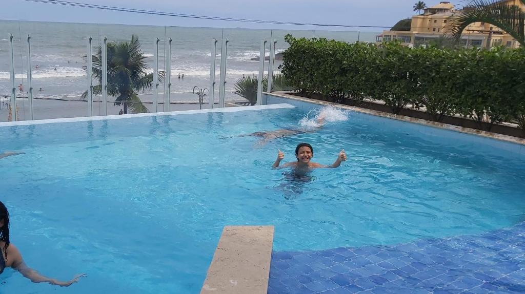 a woman swimming in a swimming pool next to the beach at APTO NOVO PÉ NA AREIA - Praia do Sonho, Itanhaém in Itanhaém