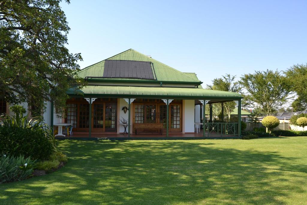 a house with a green roof and a grass yard at Lekkerrus guesthouse in Krugersdorp