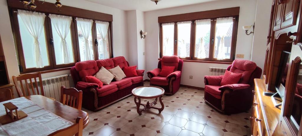 sala de estar con sillas rojas y mesa en La Herrén ,Apartamento en Panes- Entre Mar y Montaña, en Panes