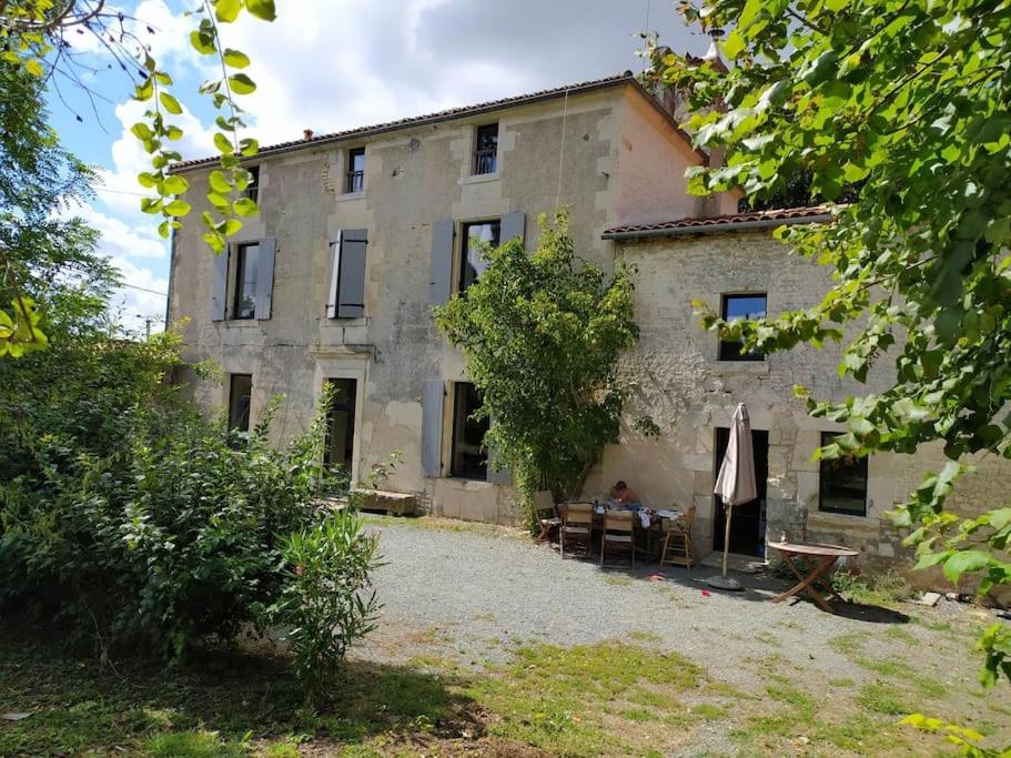 une ancienne maison en pierre avec une table en face de celle-ci dans l'établissement Maison de Famille, grand jardin et piscine fermée, à Fontenay-le-Comte