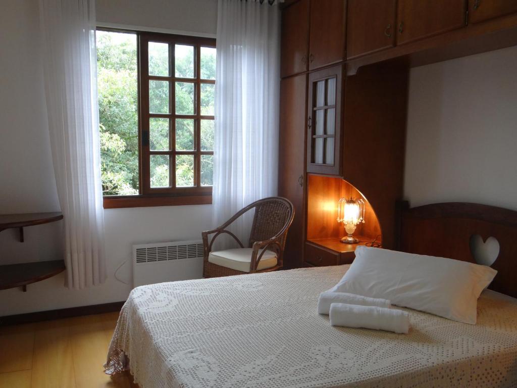 Un dormitorio con una cama y una ventana y una silla. en San Pietro, en Gramado