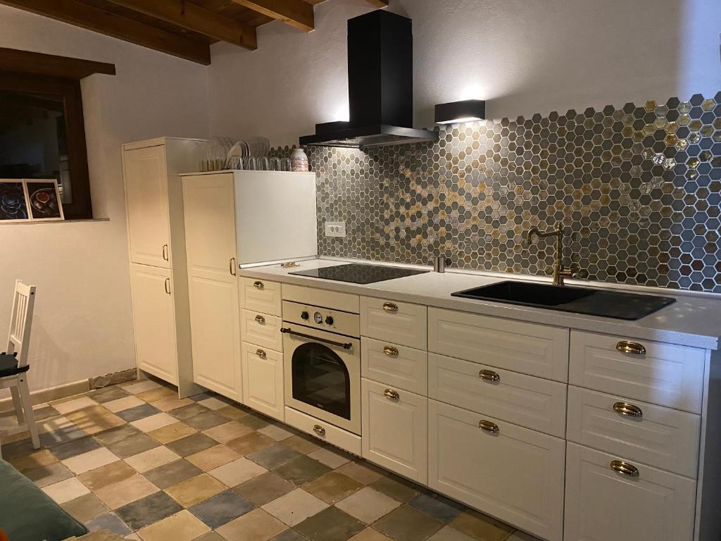 Una cocina con gabinetes blancos y un horno de estufa. en La Cuadra de Pascuala, en Tajace de Abajo