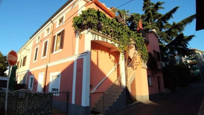 een roze en wit huis met een trap en een stopbord bij Apartmaji Sonček Izola in Izola
