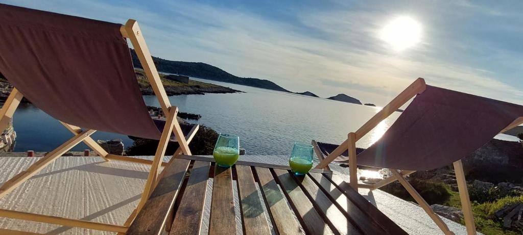 two glasses of green juice sitting on chairs next to the water at Seaside cottage 'Little white port' in Lučica