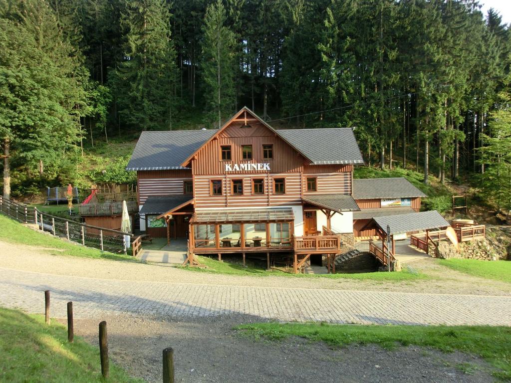a large wooden house on a hill with trees at Penzion Kaminek in Rokytnice nad Jizerou