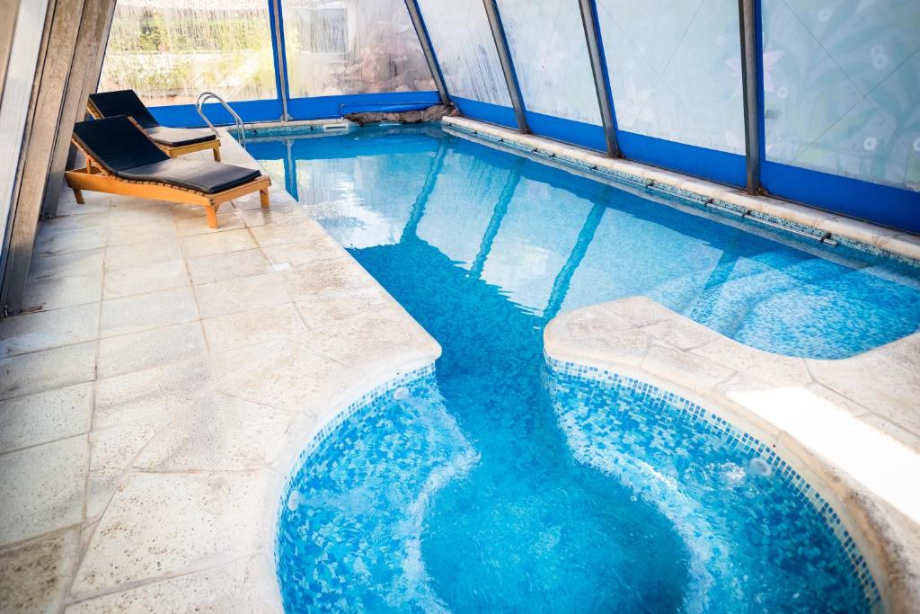 a swimming pool with two chairs and blue water at Altos del Champaqui in Villa Carlos Paz