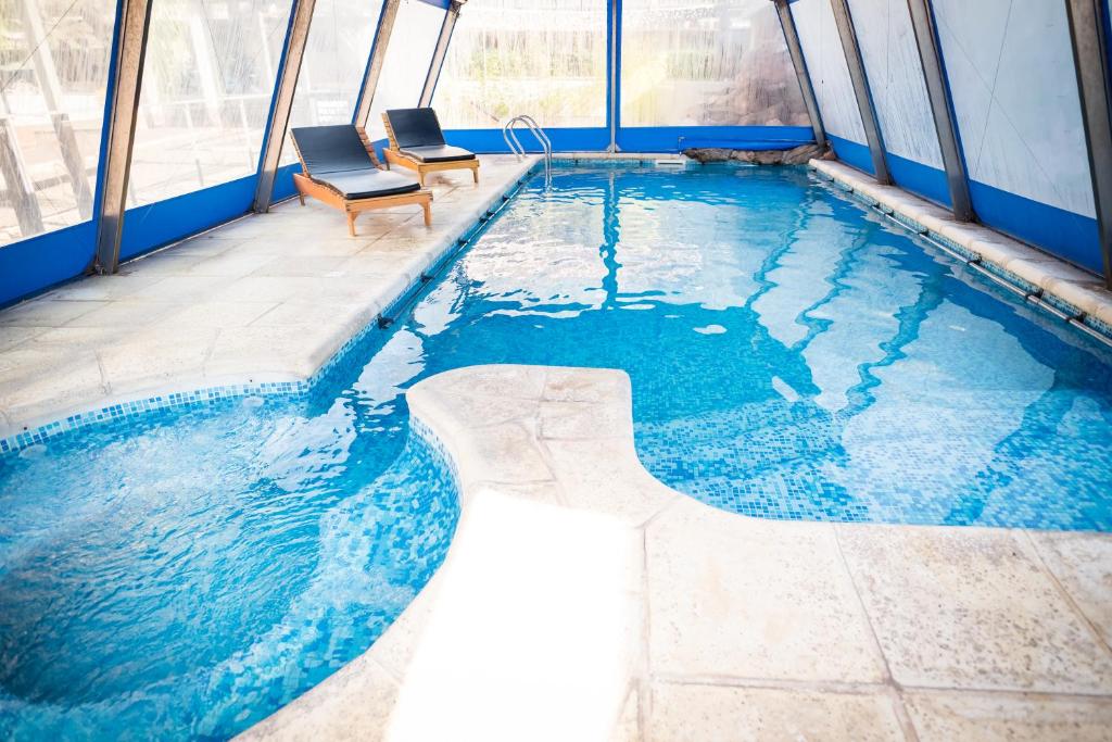a swimming pool with two chairs in a building at Altos del Champaqui in Villa Carlos Paz