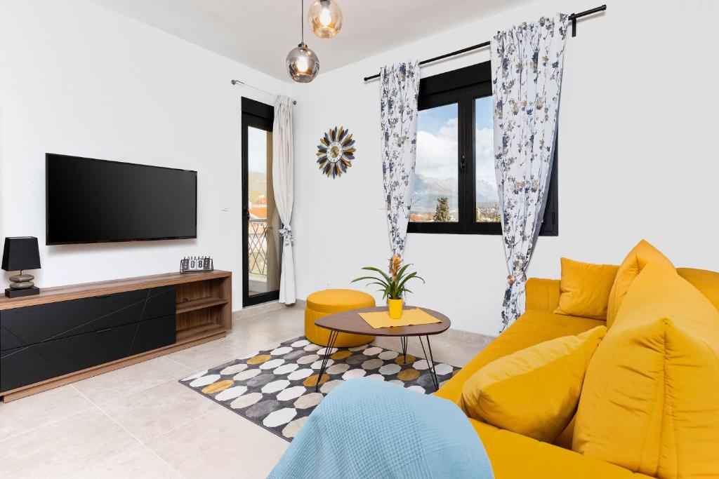 a living room with a yellow couch and a tv at Ell Star Apartment in Tivat