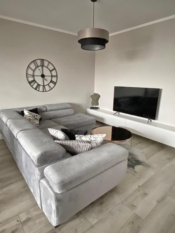 salon z kanapą i zegarem na ścianie w obiekcie Apartament Złote Noce w mieście Augustów