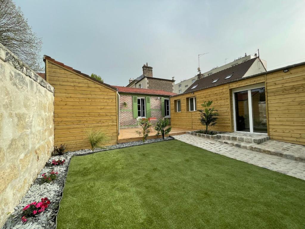 une arrière-cour d'une maison avec une pelouse dans l'établissement la casa verde 2 chambres 2 salles de bain 2 wc jardin, à Compiègne