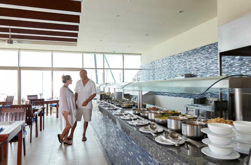 a man and woman standing in a kitchen with food at Desire Riviera Maya Resort All Inclusive - Couples Only in Puerto Morelos