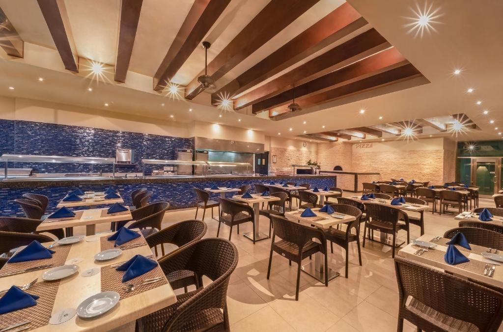 a restaurant with tables and chairs and a bar at Desire Riviera Maya Resort All Inclusive - Couples Only in Puerto Morelos
