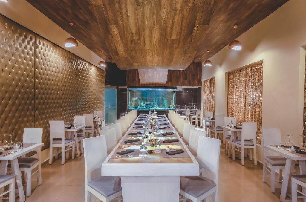 a dining room with a long table and white chairs at Desire Riviera Maya Resort All Inclusive - Couples Only in Puerto Morelos