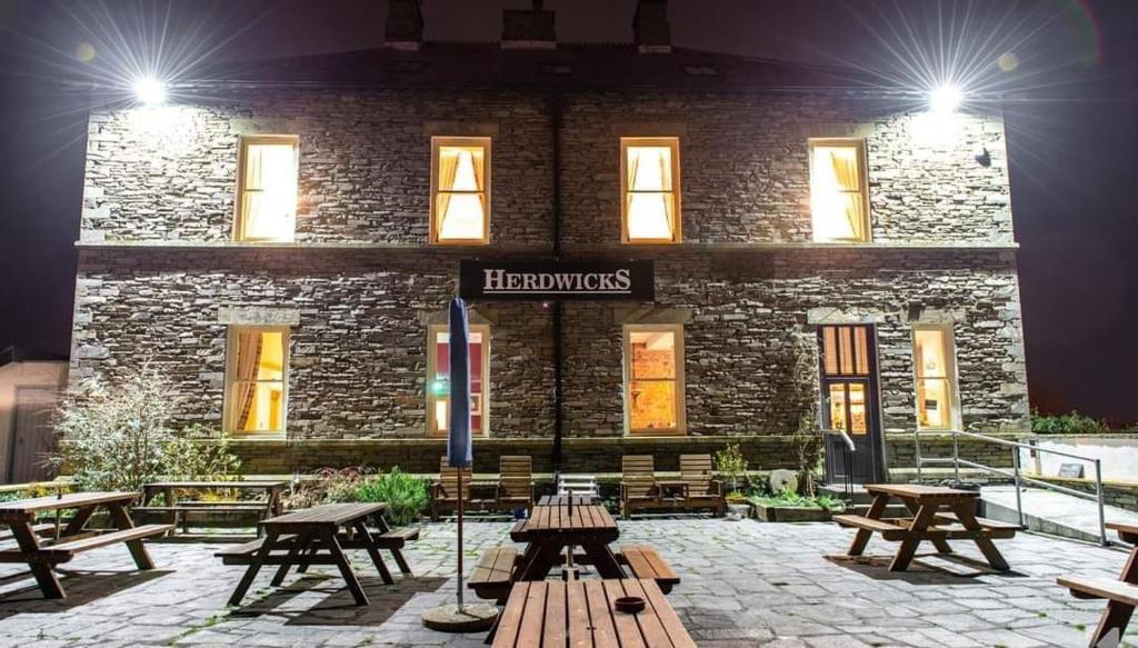 a group of picnic tables in front of a brick building at Herdwicks in Millom