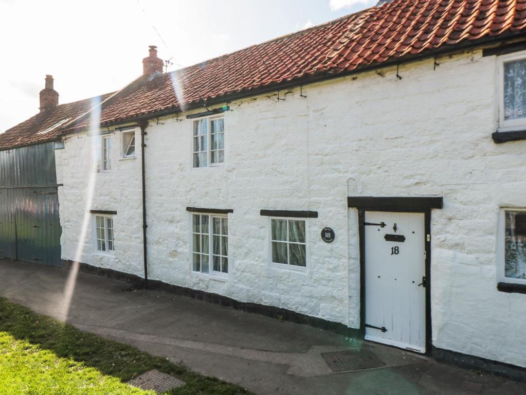 een wit gebouw met een deur en een sprinkler bij Keep Cottage in Pickering