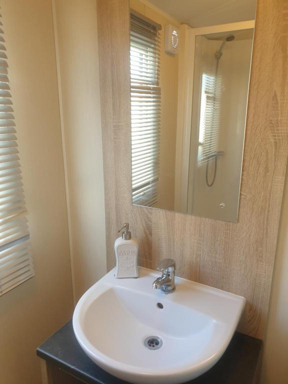 een badkamer met een witte wastafel en een spiegel bij Griffiths, Seaview Caravan Park, Whitstable in Kent