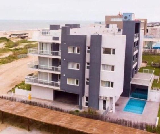 a large white building with a pool next to the beach at Departamento Apart Espacio Marina in Villa Gesell