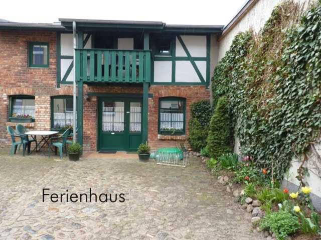 een bakstenen huis met een groene deur en een patio bij Ferienhaus "Innenhof" Objekt ID 13839-8 in Waren