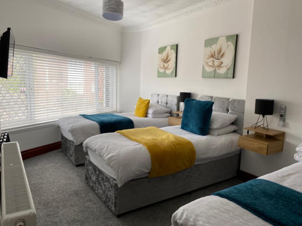 a bedroom with three beds with blue pillows at Cosy 2 Bed Flat 1 in Swansea - Home away from Home in Swansea