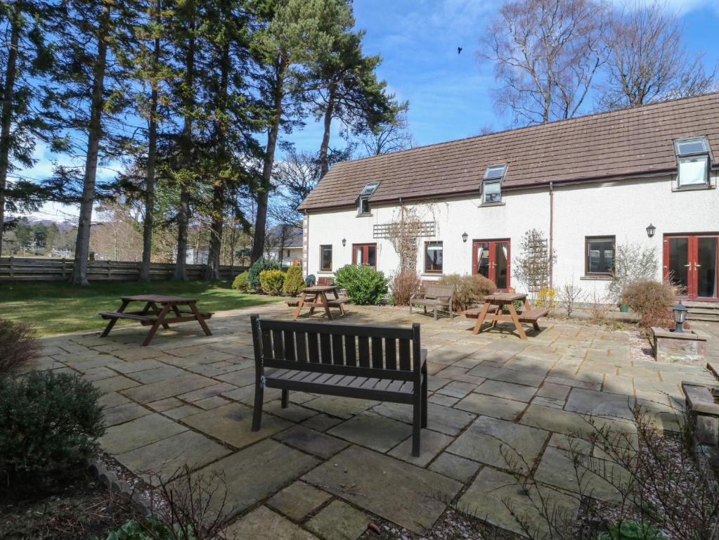 a group of picnic tables and a bench in front of a building at The Coach House in Newtonmore