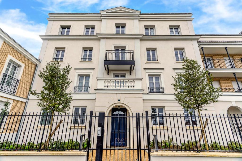 Un edificio blanco con una valla delante. en *DISNEYLAND-SERRIS* Studio Cosy, en Serris