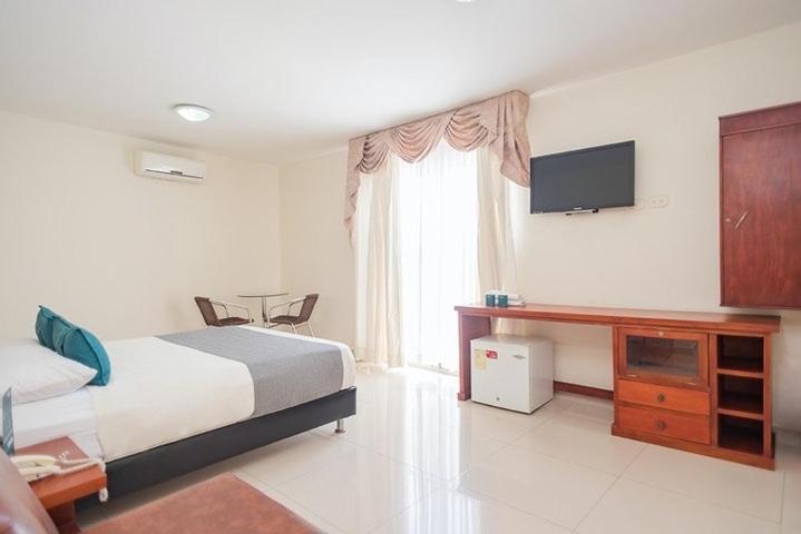 a hotel room with a bed and a television at Hotel Rivera Del Mar in Barranquilla