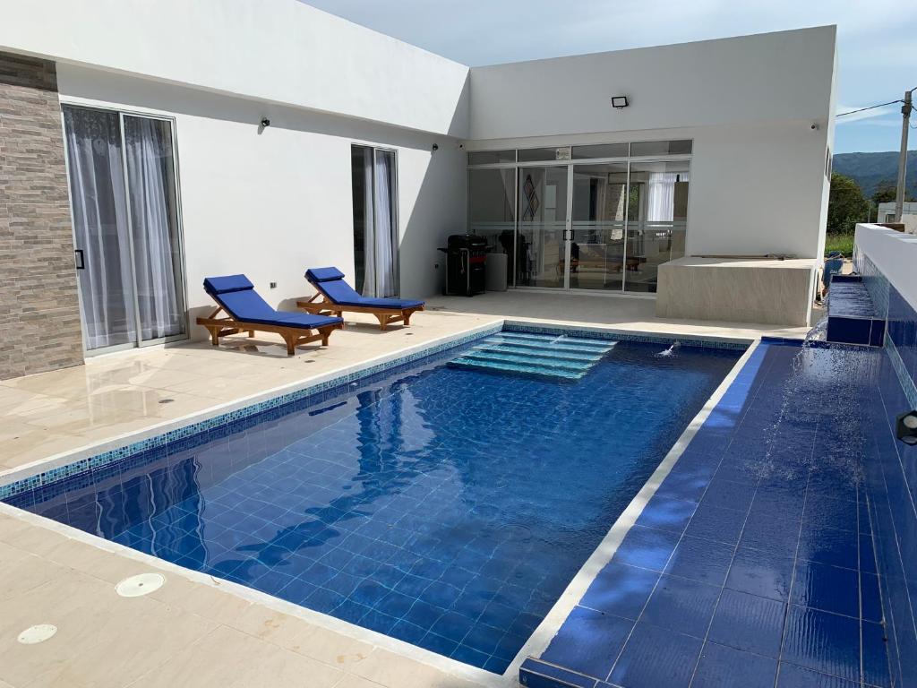 a swimming pool with two blue chairs in a house at El Olimpo 307 in Carmen de Apicalá