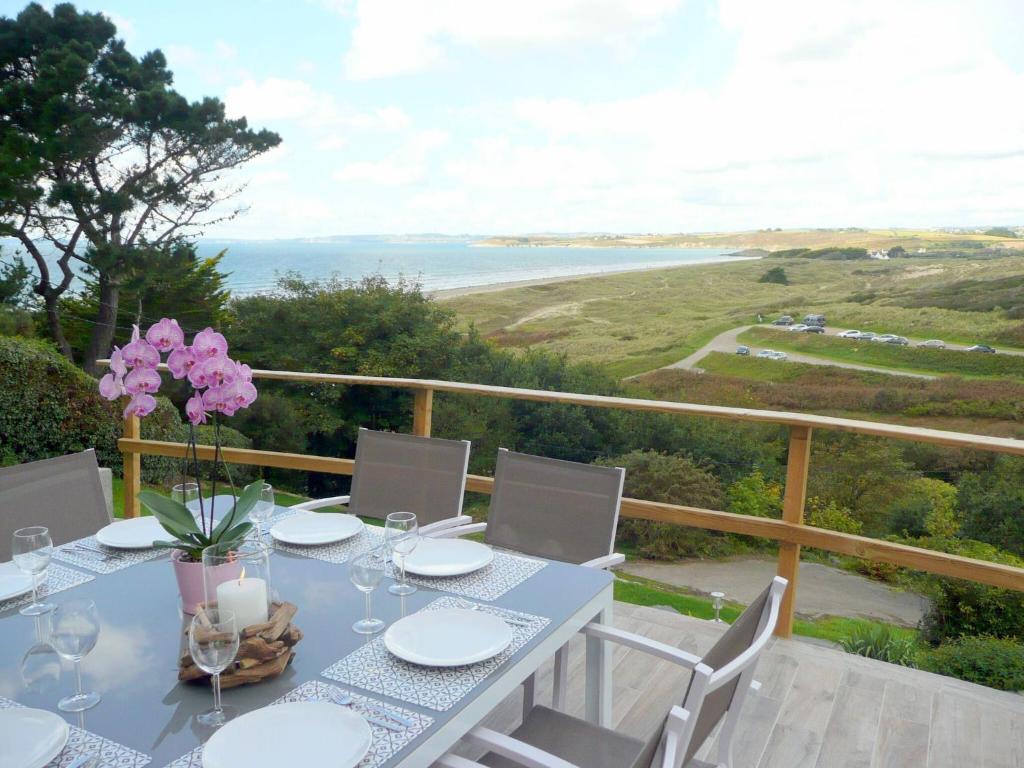 a table with white plates and pink flowers on a balcony at Stone House in Brittany with Sea Views in Plonévez-Porzay