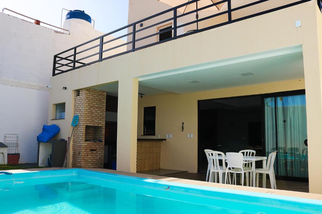 a house with a swimming pool and a patio with chairs at Magnífica casa na aruana c/ churrasqueira/piscina in Aracaju