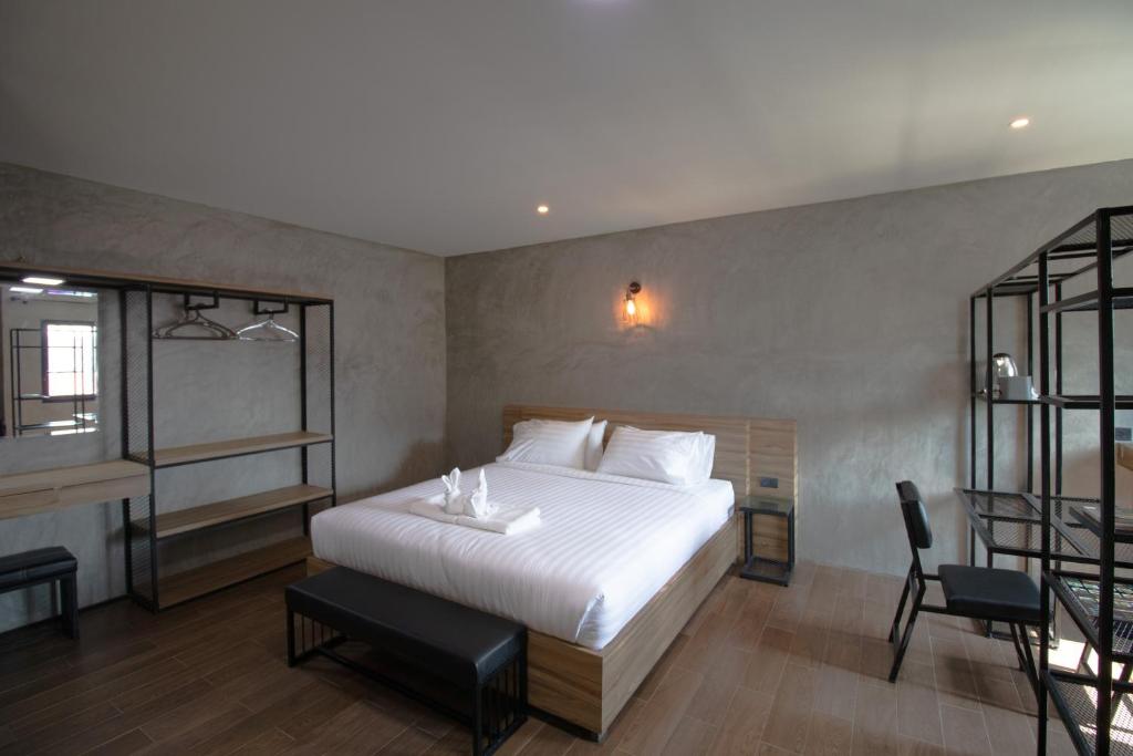 a bedroom with a white bed and a chair at Rabbit Hotel Phimai in Phimai