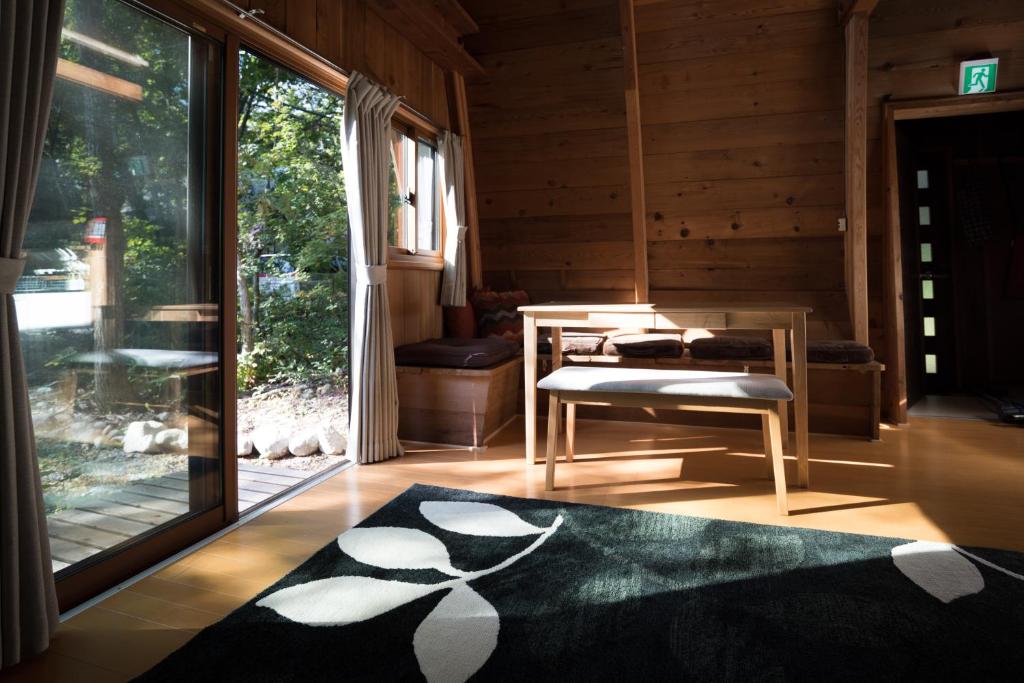 a living room with a table and a large window at Yukiita Lodge in Hakuba