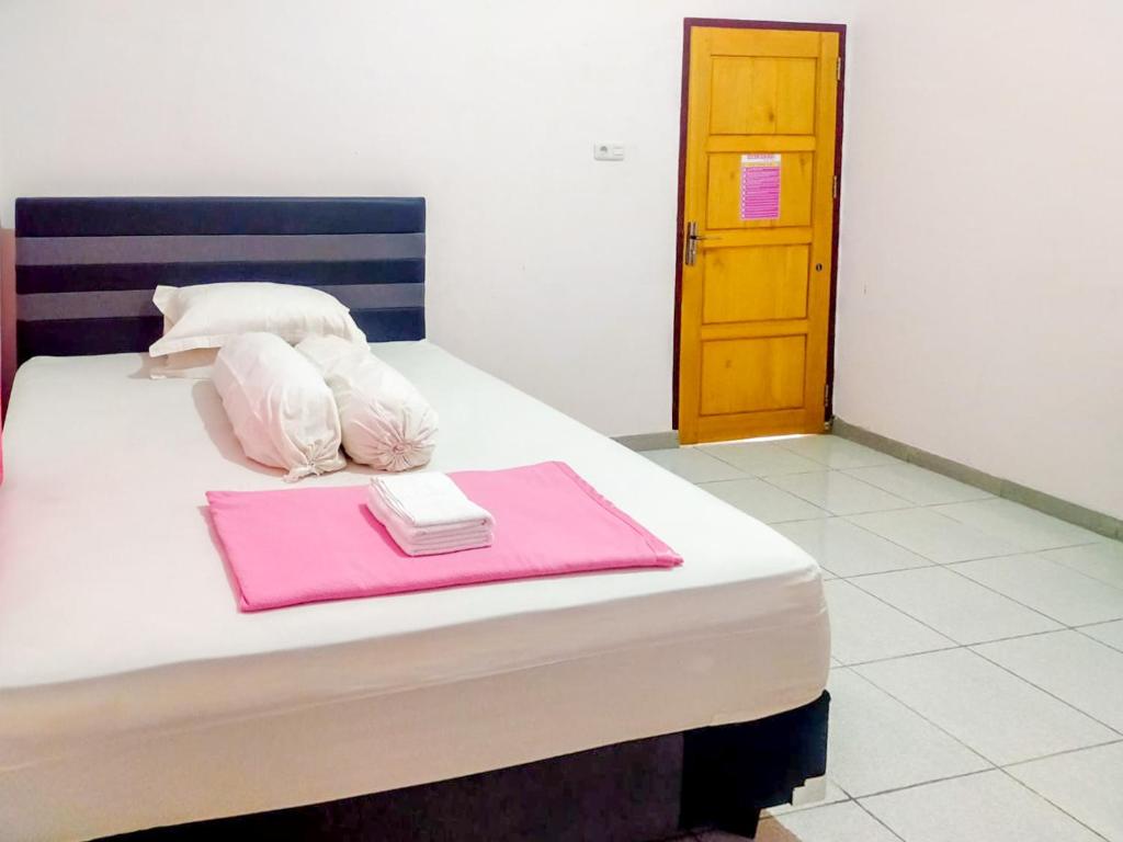 a bedroom with a bed with pink towels on it at RedDoorz @ Makarios Hotel Poso in Poso