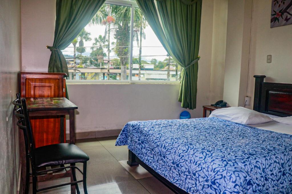 1 dormitorio con cama y ventana en Hotel Real Amazónico, en Puyo