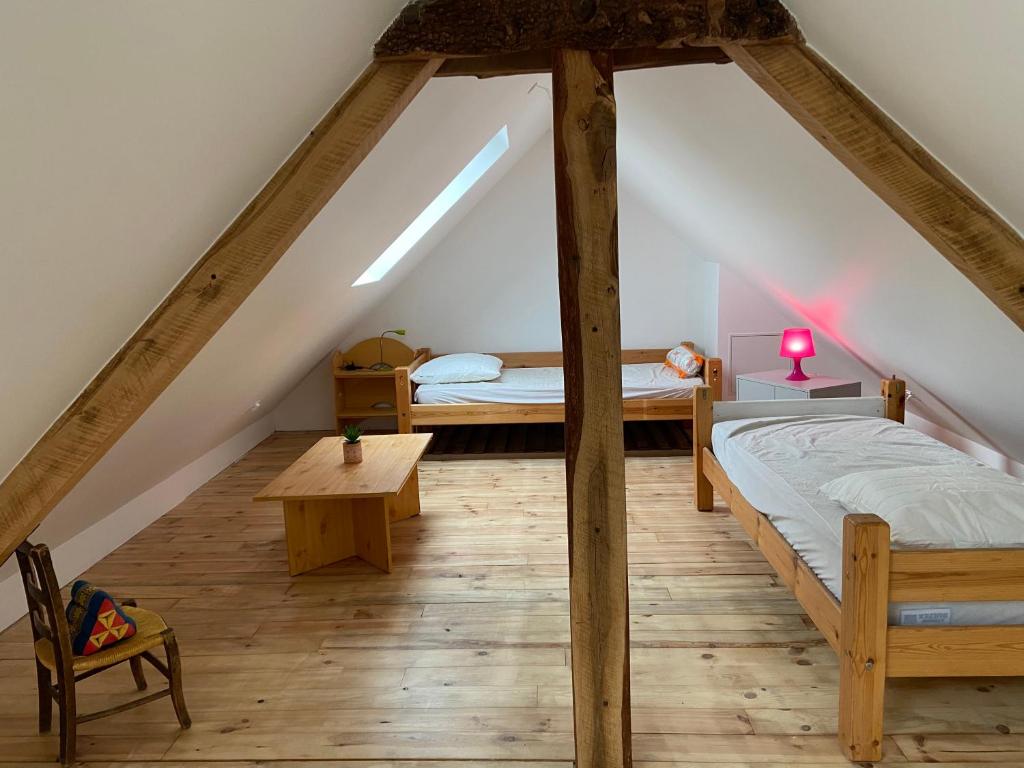 a attic bedroom with two beds and a table at La Bulle du Quinze in Mazaye